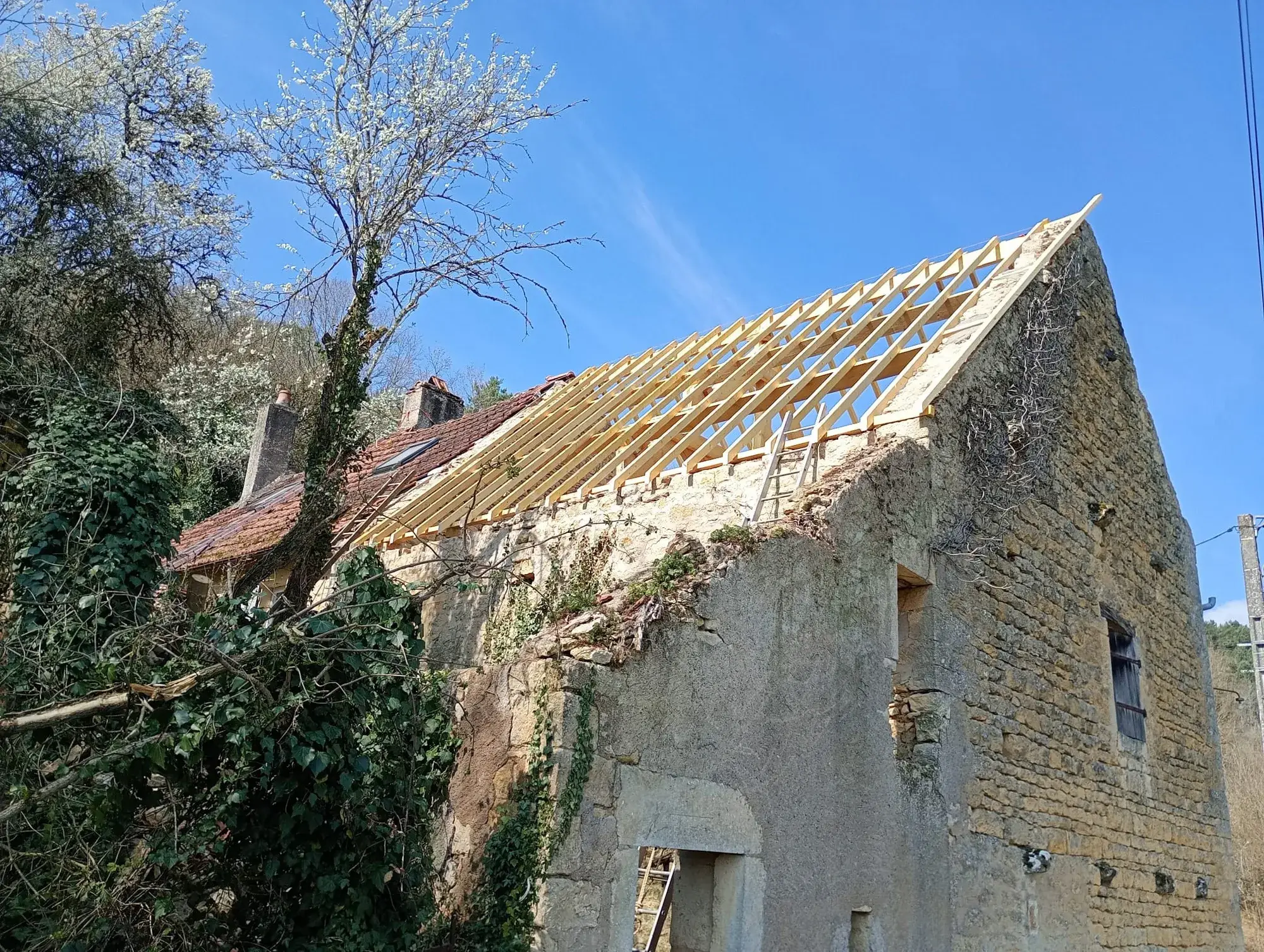 Rampant entièrement chevronné en sapin neuf sur une grange en pierre calcaire, avant pose des tuiles