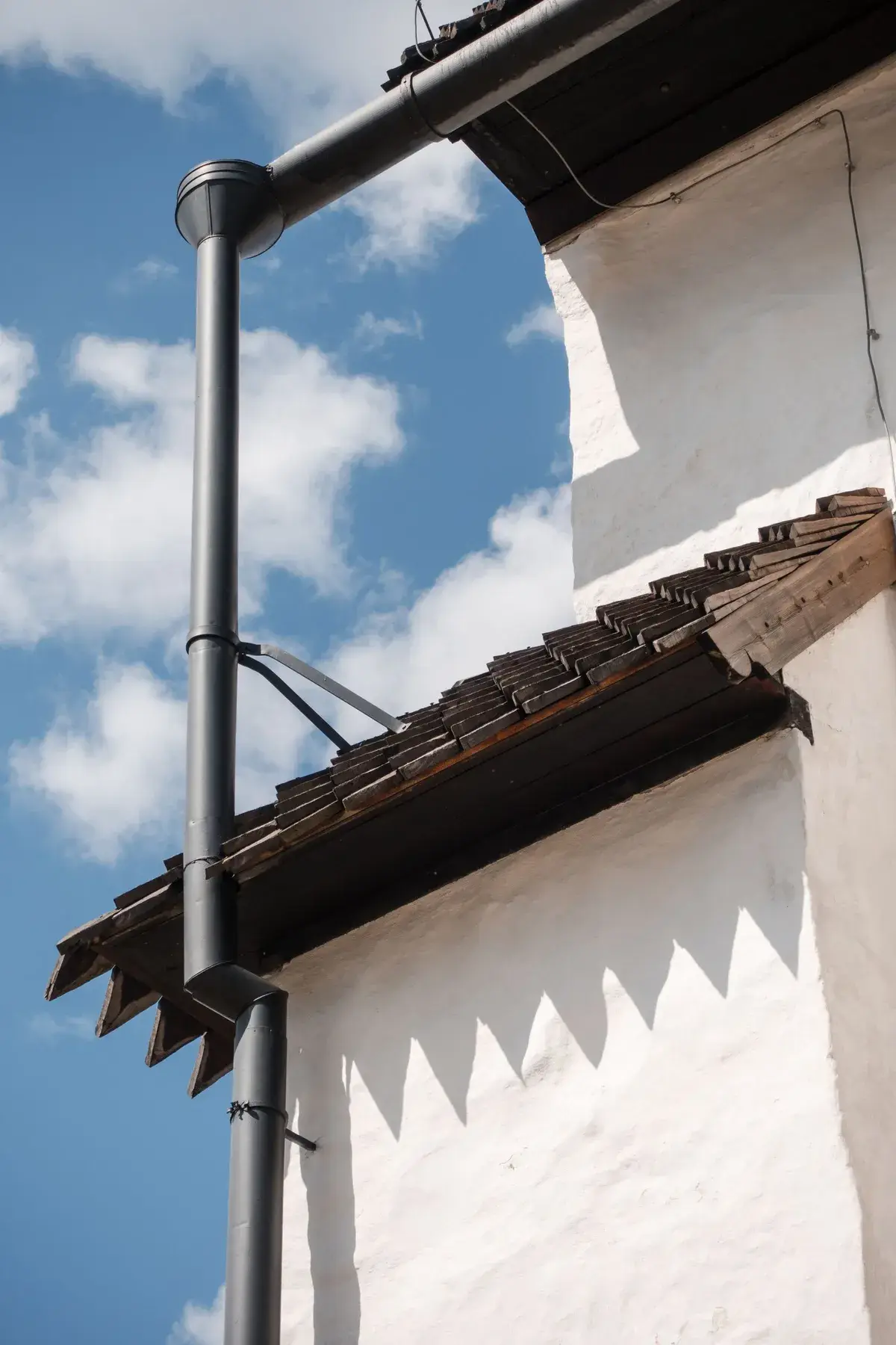Gouttière et descente neuves posées sur une maison ancienne