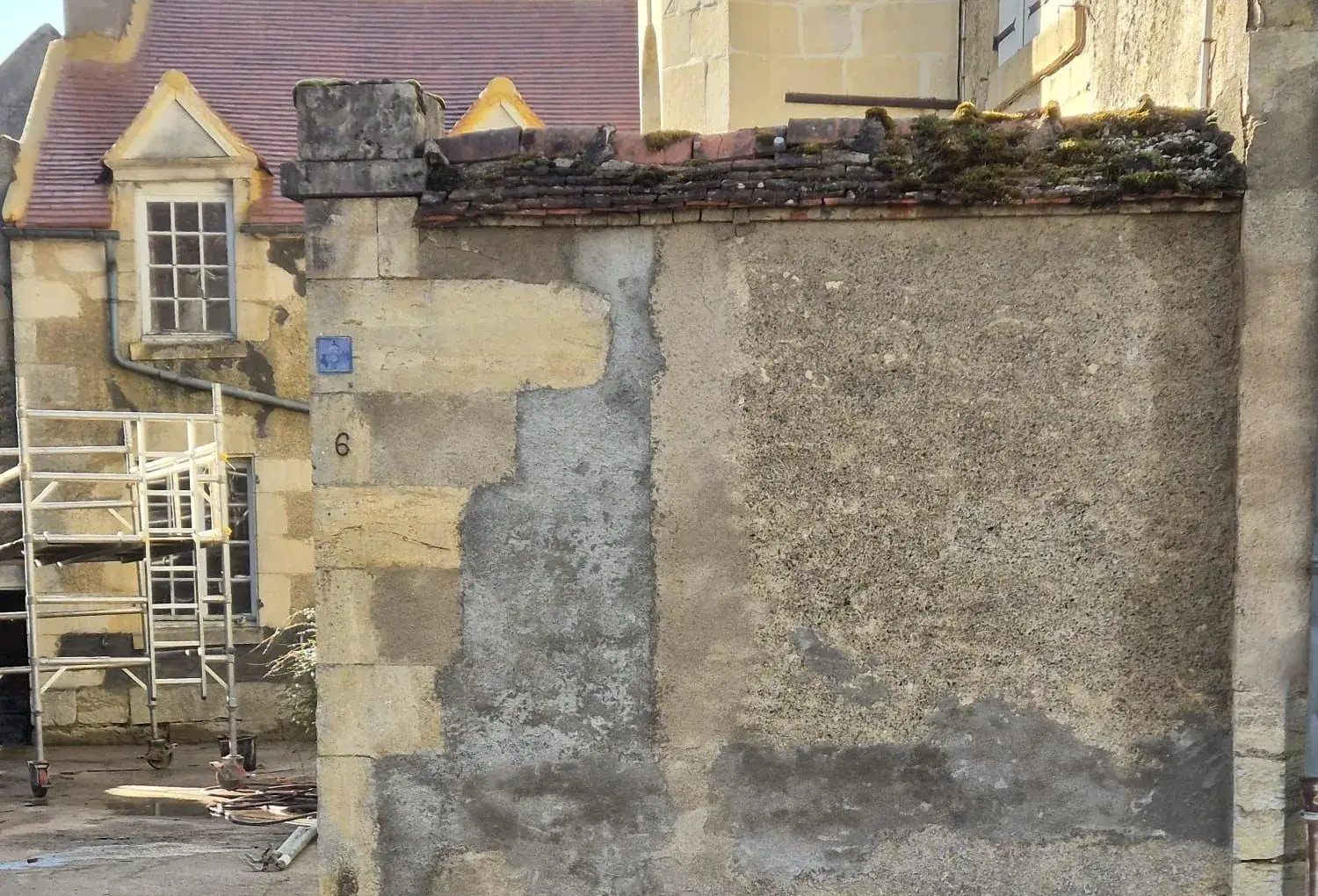 Mur de clôture avant rénovation : couronnement en vieilles tuiles moussues et enduit dégradé