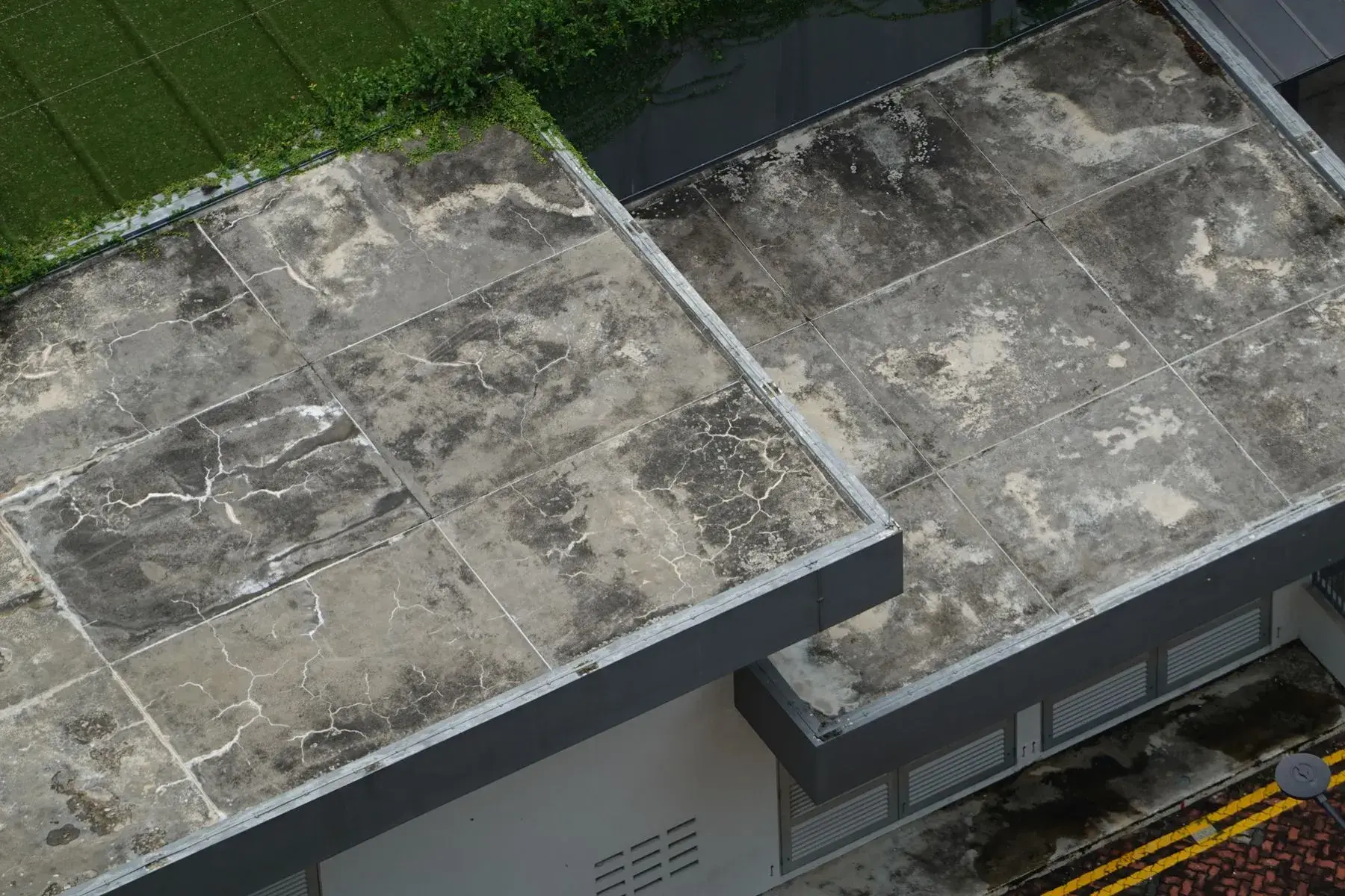 Toiture-terrasse en béton nu, fissurée et tachée par les infiltrations